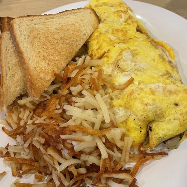 A breakfast plate with a golden omelet, crispy hash browns, and two slices of toasted bread.